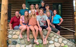 Large family at Cedar Point Resort sitting on stone steps in front of a cabin